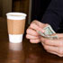 Man paying for a cup of coffee (© fStop/Getty Images)